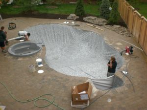 A pool install team working on putting in the liner for a backyard custom pool