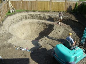 A pool installation team digging out a backyard pool