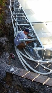 A pool crew team member working on the custom plumbing for a swimming pool installation