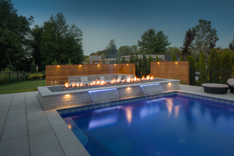 An outdoor firepit outside a swimming pool designed by Pool Craft